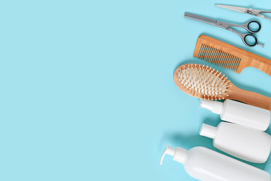 Hair care and styling products arranged on blue background with copy space