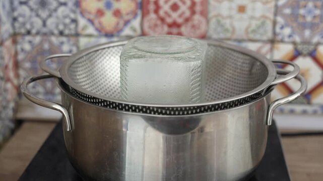 Glass jar sterilization with steam and water drops running down glass in home kitchen