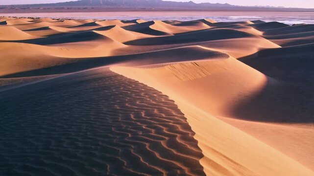 Taking off aerial drone revealing vast dunes at sunrise, showing rippled crests and slipfaces