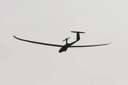 Motor glider silhouette taking off against a pale sky