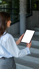 Woman in business attire using a tablet computer outdoors near a modern building © shine.graphics