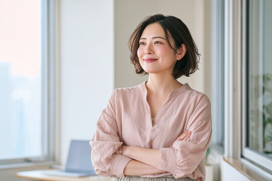 窓辺で腕を組み微笑む前向きな女性