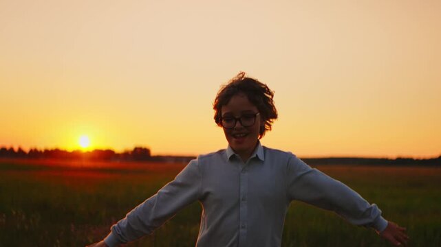 Joyful child running through open field at sunset, laughing with arms outstretched in warm golden light, celebrating freedom, nature, and carefree childhood moments
