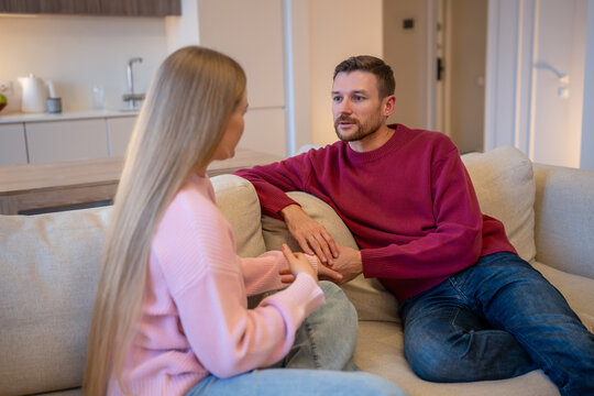 Married couple in conversation together on sofa, man listening to woman partner with attention and concern, male and female partners during serious conversation on couch, empathy and support in family