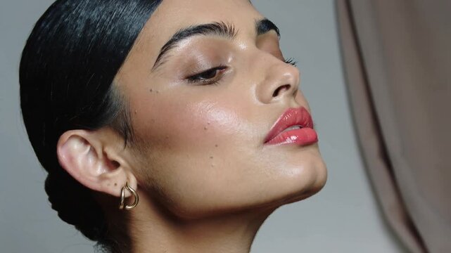 Reacting to camera cue, model lifting chin, closing eyes in studio, red-lipstick and gold earring
