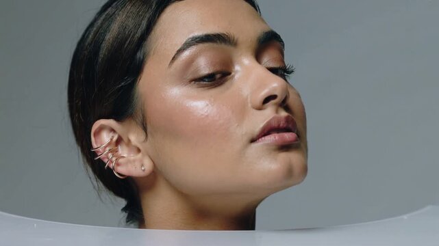 Rising adult woman responding to frame sequence behind rim in studio, showcasing gold ear cuffs