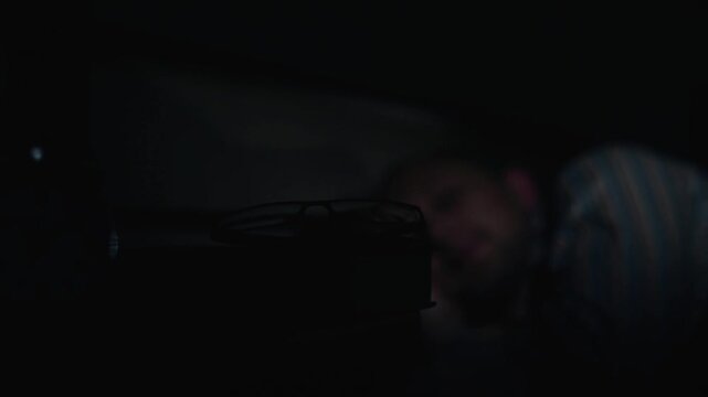 Man Turning Off Bedside Lamp and Going to Sleep at Night