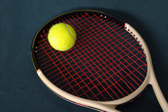 Tennis racket and yellow ball on court surface