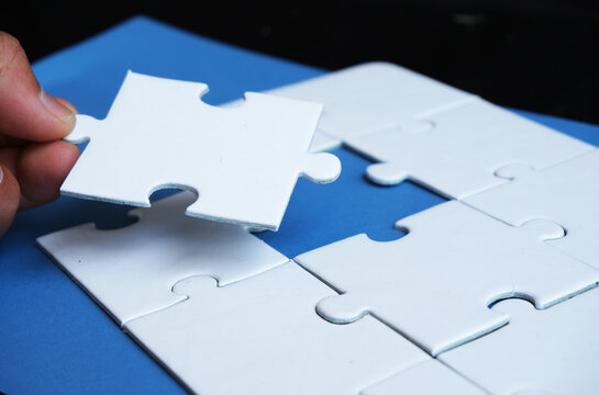 A hand attempts to fit in a missing puzzle piece, symbolizing alliance, unity, teamwork, solutions, success, and problem-solving. It serves as a metaphor for business integration or the challenge of a