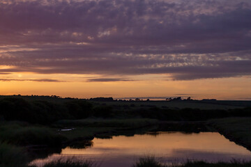 Obraz premium Brighton, England – May 22, 2022: Dramatic sunset reflected in peaceful countryside pond