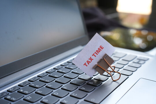 A note reading "TAX TIME" is clipped to the top of a keyboard with a paper clip&mdash;a concept for a tax payment reminder.