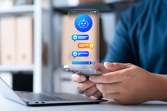 AI chatbot assistance concept. Man holding smartphone with virtual hologram chat interface and robot icon for digital communication, customer service, and futuristic technology in office workspace.