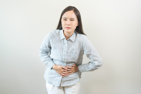 Flatulence asian young woman intolerance hand in stomach ache, suffer from food poisoning, abdominal pain and colon problem, gastritis or diarrhoea when at home. Patient belly, abdomen or inflammation