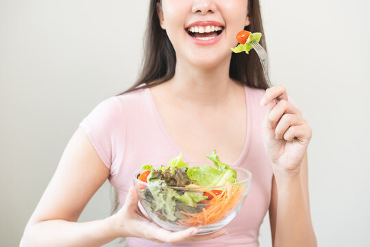Diet concept, happy smile asian young woman use fork to prick tomato, fresh vegetable or green salad, eat nutrition food isolated on background, low fat to good body, getting weight loss for healthy.