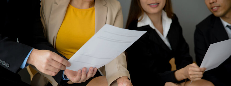 Business professionals reviewing and point document during teamwork meeting. Group of businesspeople collaborate with hand gestures, discussing plan and paperwork in corporate office workplace.