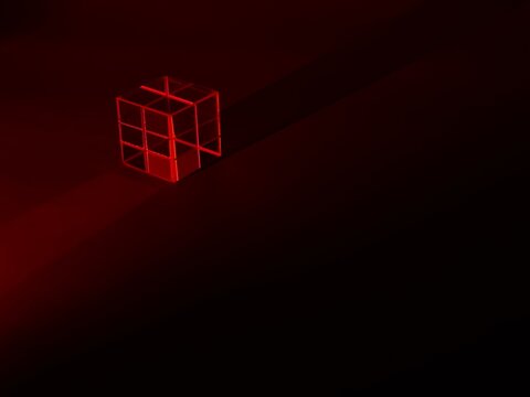 Transparent geometric cube illuminated by intense red light with a long dramatic shadow on a dark abstract