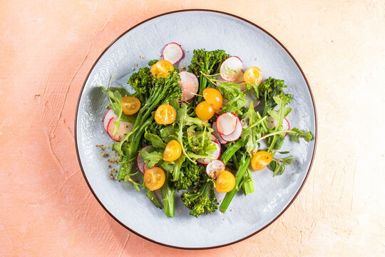 Grilled green spring vegetables: radish, tomato, broccolini on stone background.