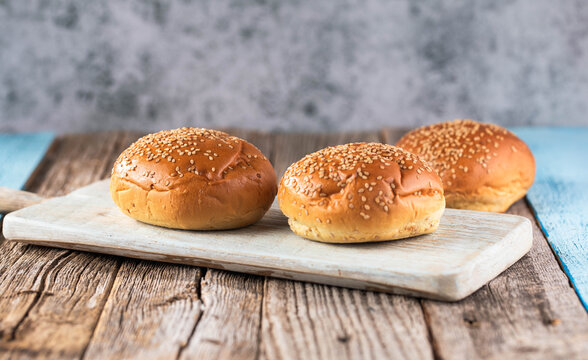 Empty burger bun with sesame seeds on a kitchen table.
