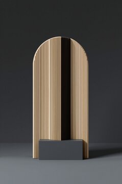 An arched wooden room divider with vertical fluted slats, standing on a dark grey rectangular base against a dark grey wall in a studio space