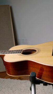 Vertical video: Moving camera showing six-string guitar on stand with mic in studio, for recording
