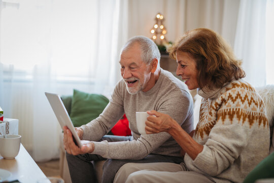 Senior couple making Christmas video call with family during holidays at home.