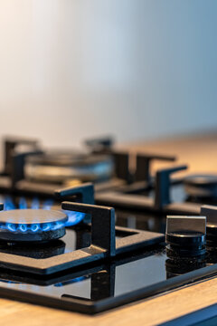 Gas cooktop burner with blue flame. Close vertical detail with copy space.