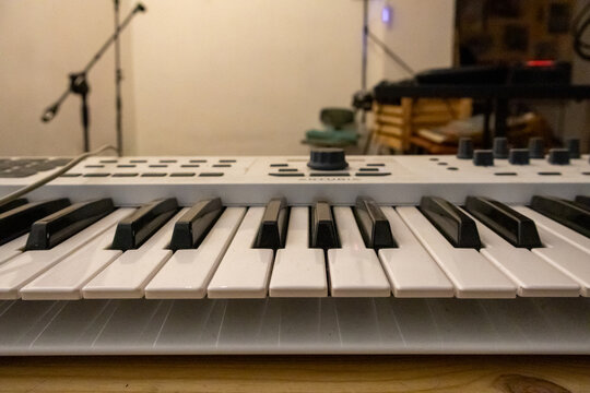 Electronic MIDI keyboard controller with black and white synth keys on wooden table close up view photo