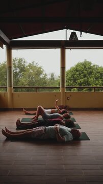 Students lying on mats in corpse pose during a spiritual retreat session at a wellness center