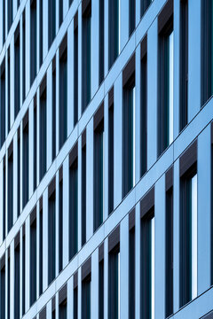 Blue modern facade with repeating vertical windows and geometric lines forming an abstract architectural pattern across a contemporary building exterior
