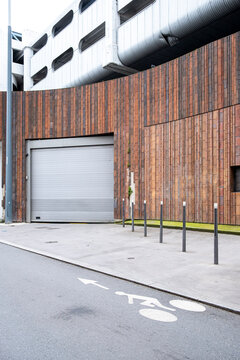 Urban bicycle lane beside modern building with wood facade and garage entrance showing cycling mobility infrastructure in an everyday street setting