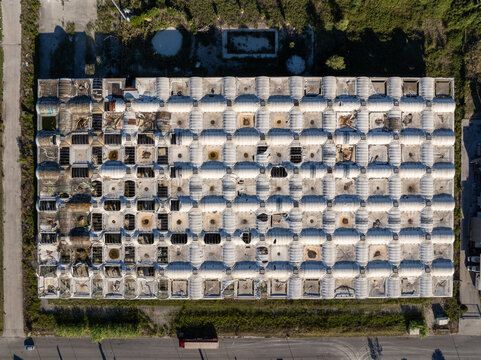 Aerial view of the modular grid roof of an industrial building with weathered sections and skylights in Ancona, Marche, Italy.