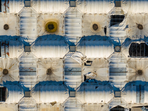 Aerial view of the modular white roof structure with repeating geometric panels, circular vents, and areas of wear and tear, Ancona, Marche, Italy.