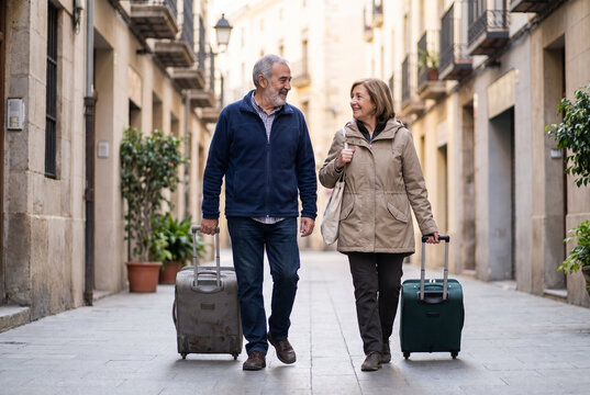 Pareja s&eacute;nior viajando con maletas por una calle urbana durante sus vacaciones