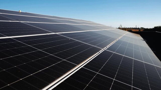 Rows of solar panels extend across a rooftop under clear sky. Solar energy, clean electricity, renewable power and sustainable energy concept.