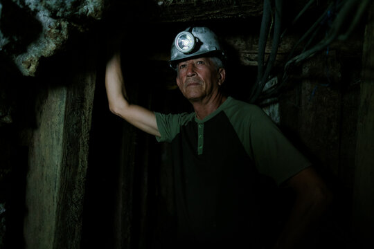 Miner working underground, exploring dark cave tunnel