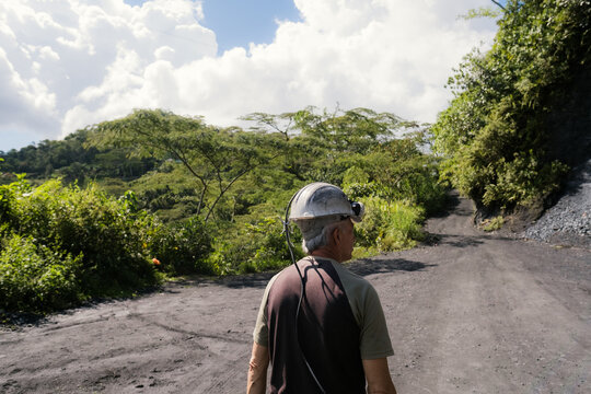 Older miner wearing hard hat walking on a dirty road