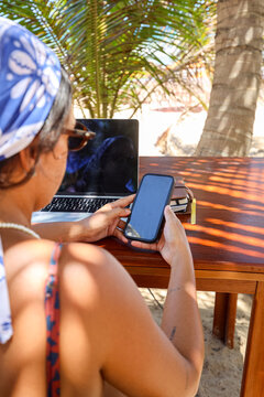Freelancer checking phone under palm trees at seaside