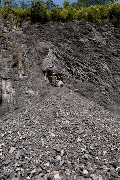 Man exploring dark rocky shale quarry with rubble pile
