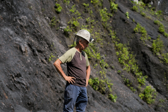 Miner overlooking rural landscape and coal mining in mountains