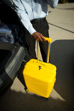 High angle view of professional with suitcase near the trunk of car.