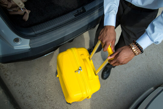 High angle view of professional with suitcase near the trunk of car.