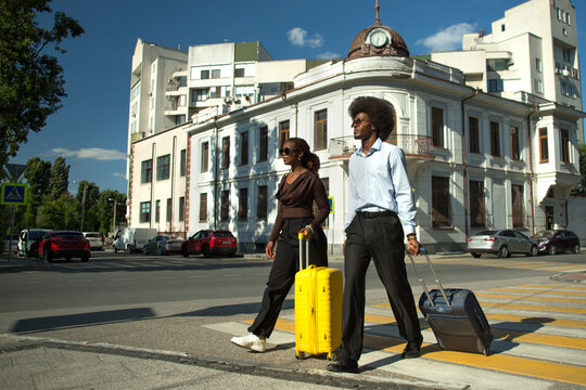 Two Black professionals with suitcases in business trip.