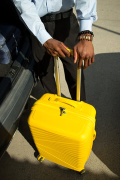 High angle view of professional with suitcase near the trunk of car.