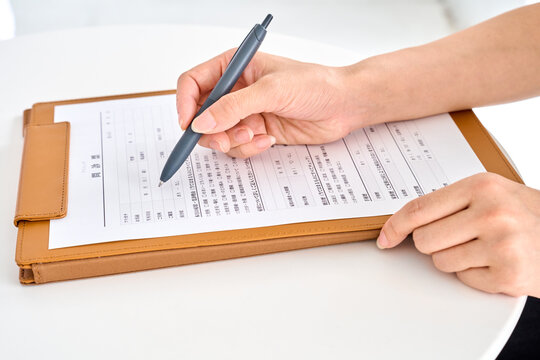 問診票を書く患者の女性の手元