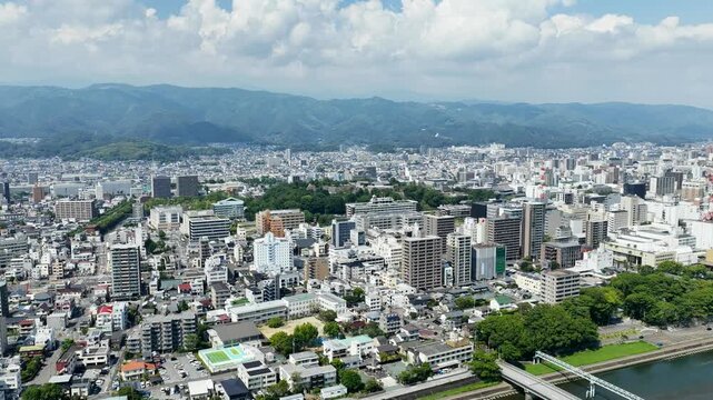 Aerial drone footage over urban cityscape with river and mountains in Kochi, Japan