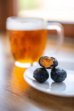 Black fried snack balls with spicy filling served with beer