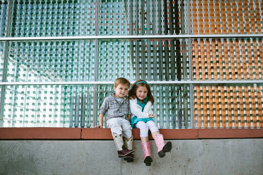 Brother and sister sitting on wall