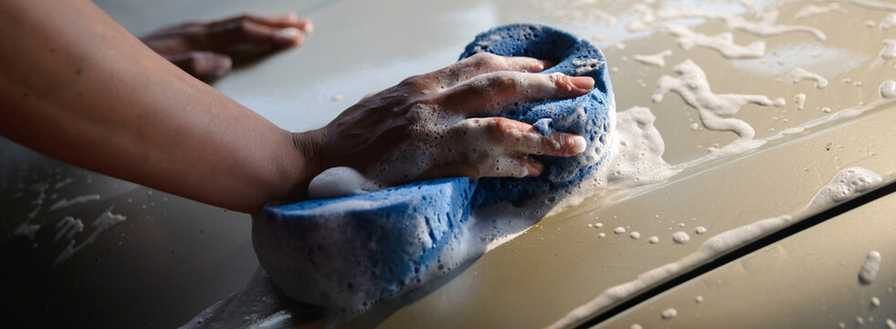 Car cleaning with sponge and soap, hand washing vehicle exterior for car wash, auto care and maintenance, showing foam and suds on automotive surface during manual cleaning-banner.