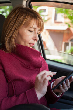 Mid adult business woman using smart phone in a car