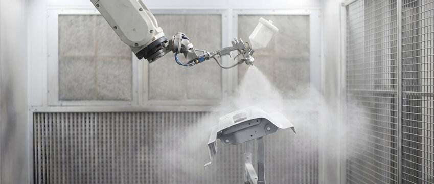 An industrial robotic arm sprays coating onto a component inside a closed paint booth for automated manufacturing.